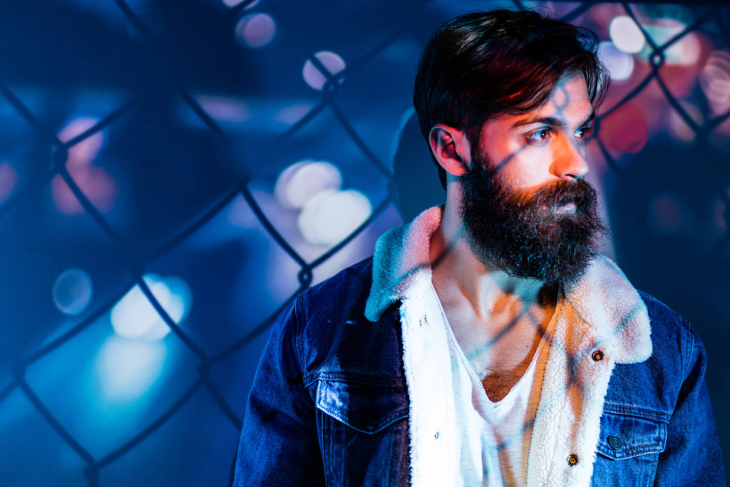 Fence and city lights projected on a man's upper body.