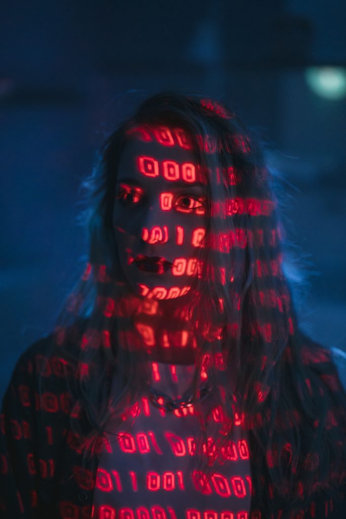 A woman in a darkened room with projections of red light on her face